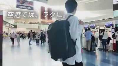 リュックからスーツケースへ切り替える様子。広い空港内を歩きながら、片手でキャスターを瞬時に展開し、ハンドルを出して転がして進む一連の流れ。
